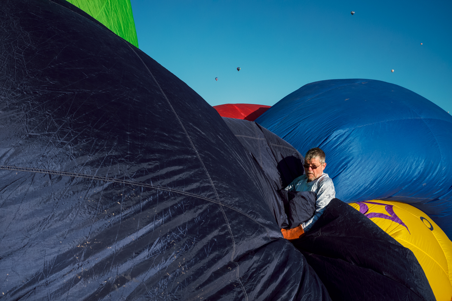 A man stands amidst large segments billowing of billowing blue fabric 
